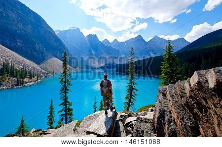 Man hiker on cliff over blue alpine lake. Moraine Lake. Banff National Park. Rocky Mountains. Alberta. Canada.