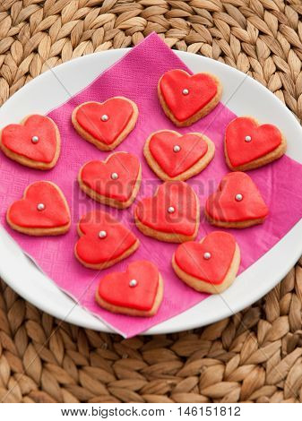 Homemade heart-shaped red cookies decorated with red icing. Vertical shot