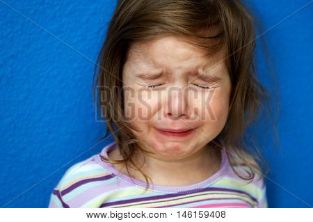 A little girl whose Chicken Pox are just starting to show stands crying her eyes out. She looks so sad with tight clenched eyes spouting tears.
