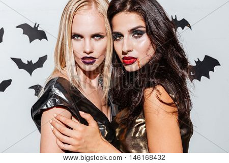 Two beautiful young women with halloween makeup standing over white background