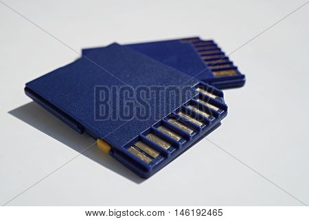 Two memory cards (SD card - Secure Digital card) used in video cameras and  computers in blue color with golden connectors as a symbol of technology used for home and professional entertainment