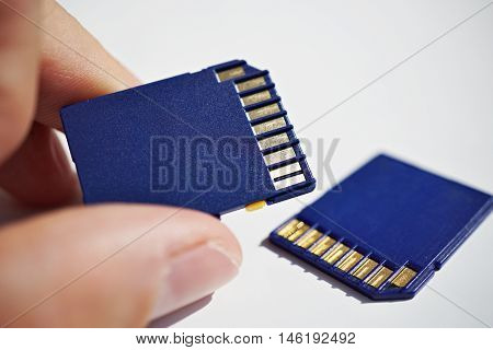 Male hand holding a memory card (SD card - Secure Digital card) used in video cameras and  computers in blue color as a symbol of technology used for home and professional entertainment