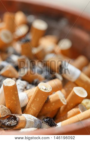 Big pile of put out cigarettes in an ashtray. Smoking smoker addiction health hazard lung cancer concept.