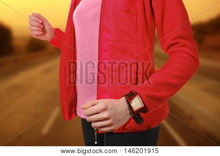Woman running with pulsometer on blurred road background