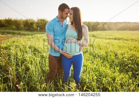Happy Pregnant Couple At Garden On Magestic Sunset