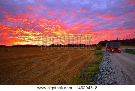 Truck and field under beautiful sunset sky.