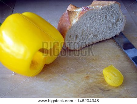 Wheat bread and yellow bell pepper on a wooden board.