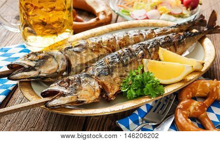 Oktoberfest menu. Grilled mackerel fish with beer and pretzel served on table