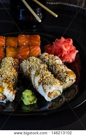 variety of sushi rolls on a black bowl with chopsticks
