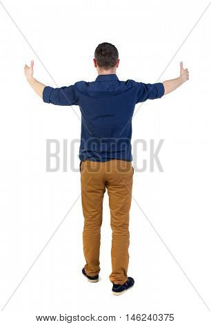 Back view of business man shows thumbs up. man in a blue shirt with the sleeves rolled up, standing arms outstretched in front of him.