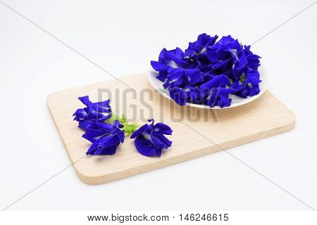 Butterfly pea flower in a cup on wooden plate on white background.