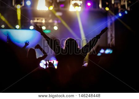 Black silhouette of young girl on rock concert, openair fest party