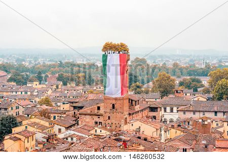 Aerial cityscape view on the old town of Lucca with Guinigi tower from the clock tower at the foggy weather in Italy