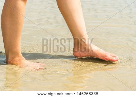 woman feet in sea water on beach