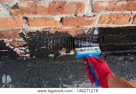 Roofer covered brick wall bitumen primer for improving adhesion during surfacing contiguity with rolled waterproofing during the installation of flat roof.