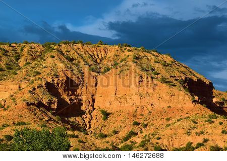 Badlands with sandstone mesas and storm clouds beyond taken at a Juniper and Pinon Pine Woodland in rural Northern New Mexico