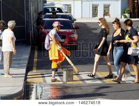 MOSCOW, RUSSIA - August 28, 2016: Janitress on a Moscow street pedestrian crossing among the passers-by. August 28, 2016 in Moscow, Russia