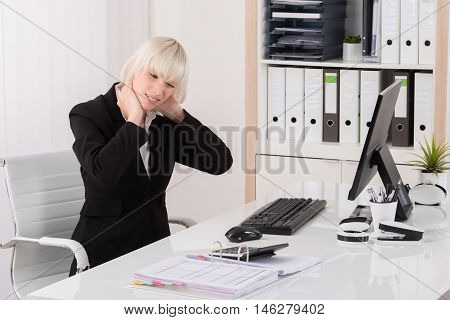 Young Businesswoman Suffering From Neckache At Desk In Office