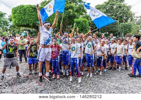Antigua Guatemala - September 14 2015: Local students cheer & run in streets with Guatemalan flags & lit torches while blowing whistles & horns during Guatemalan Independence Day celebrations