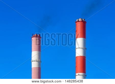 Pipe CHP chimneys against the blue sky with clouds