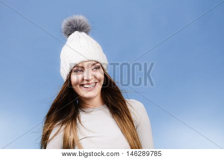 Attractive woman in winter cap and gray sports thermolinen underwear for skiing training studio shot on blue. Long sleeves top