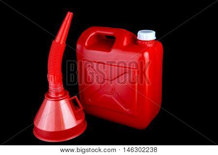 Red fuel container and funnel isolated on a black background