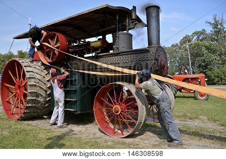ROLLAG, MINNESOTA, Sept 1. 2016: Uidentified men demonstrate the placing  of a belt on an old  steam engine fly wheel during the West Central Steam Threshers Reunion in Rollag, MN.