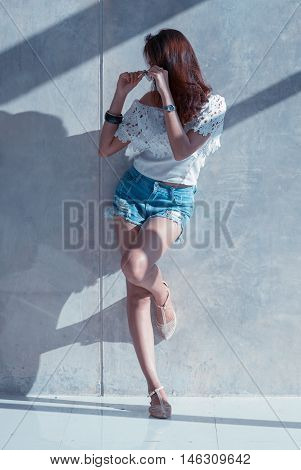 Fashion Portrait Of Young Model Posing By The Wall
