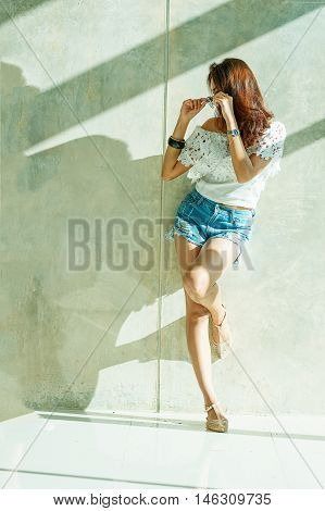 Fashion Portrait Of Young Model Posing By The Wall