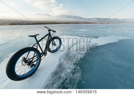 Fatbike (also called fat bike or fat-tire bike) - Cycling on large wheels. Bicycling is at sunset on the ice.