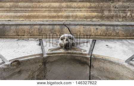 A stone skull placed near the entrance of a charnel house in an Italian graveyard.