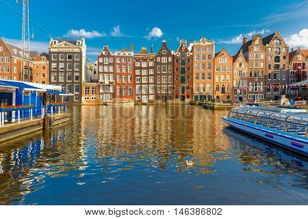 Beautiful typical Dutch dancing houses at the Amsterdam canal Damrak in the sunny evening, Holland, Netherlands.