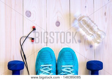 Flat Lay Shot Of Sport Equipment, Shoes, Water, Earphone On Wooden Background.