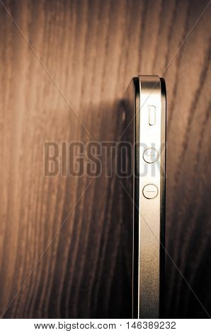 Milan Italy - September 3 2014: Apple iphone 4 smartphone on a wood surface volume buttons close up view from above