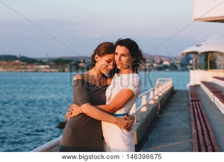 Portrait of happy mother with teenage daughter. Sunset light. Mom holding her teen daughter.