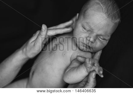 Newborn in mother's hands, black and white portrait.