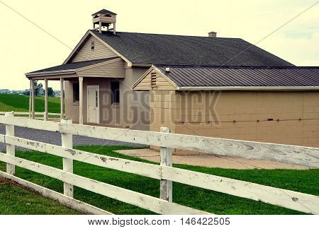 Lancaster County Pennsylvania - June 5 2015: A one-room Amish schoolhouse and buggy shed set amidst rolling farmlands on a country road