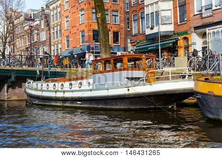 Amsterdam, Netherlands - April 1, 2016: Traditional boat house, canal, bridge in Amsterdam, Holland