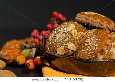 Typical Dutch filled spicy cookies with almonds on autumn colored and dark background