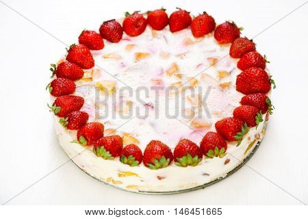 Cake with strawberries gelly yogurt and cherries shot from above. Full length. Isolated on white background