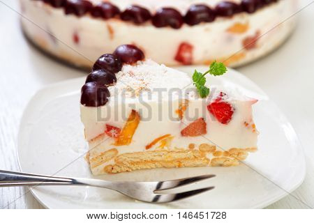 Cake with cherris gelly yogurt and fruits. Isolated on white background. One piece in a white plate. Horizonta; shot