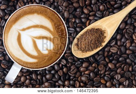 White cup of coffeeLatte art and granulated sugar in coffee beans background