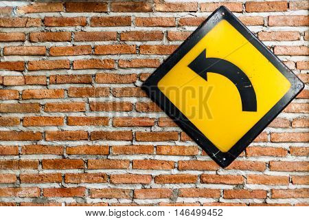 Brick wall with turn left sign on wall