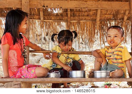 Innwa Myanmar - February 28 2011 - Three kids eating outdoors in a hut