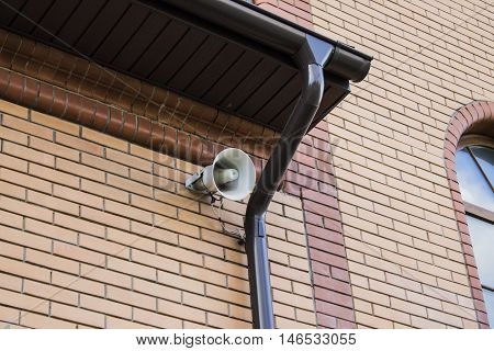 White megaphone hanging on a brick wall