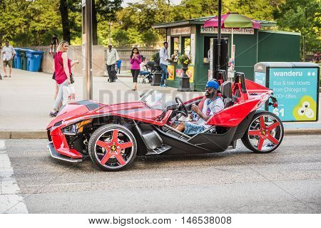 Chicago, USA - May 30, 2016: Man with cubs shirt in flashy red Polaris Slingshot Ferrari sports car on downtown street