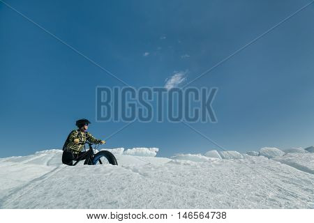 Fatbike (also called fat bike or fat-tire bike) - Cycling on large wheels. Extreme girl riding a bike on snow melted ice. The Lake Baikal.