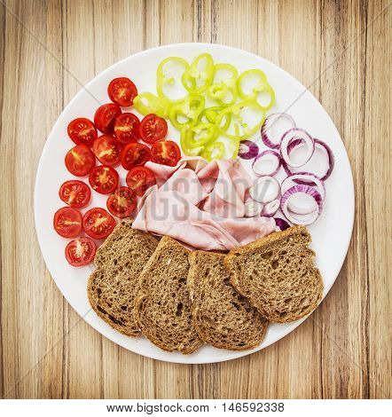 Tasty whole wheat bread with butter ham onion paprika and cherry tomatoes. Food theme. Refreshments for guests. One full portion.