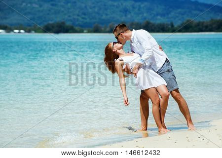 Beautiful young couple hugging and kissing on sea background