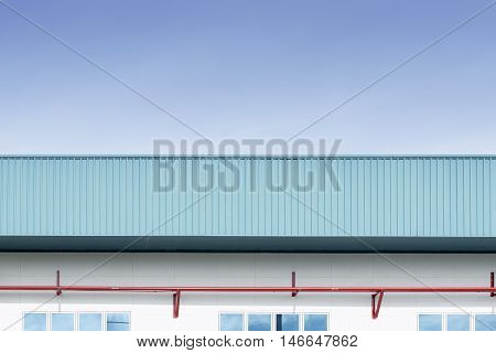 The side view of factory buildingwhich build from metal sheet.The red pipe line installed at the wall of factory building